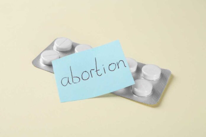 Paper,Note,With,Word,Abortion,And,Pills,On,Beige,Background,