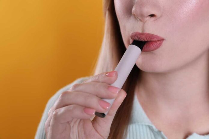 Young,Woman,Using,Electronic,Cigarette,On,Orange,Background,,Closeup.,Space