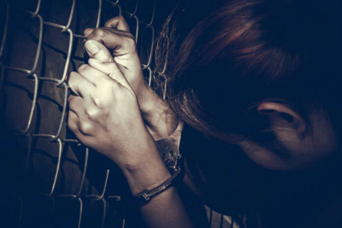 Sad,Prisoner,Woman,With,Handcuffs,Holding,Rust,Metal,Fence,With