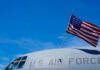 Close-up of a U.S. Air Force aircraft with an American flag waving against a blue sky