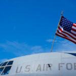 Close-up of a U.S. Air Force aircraft with an American flag waving against a blue sky