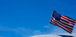 Close-up of a U.S. Air Force aircraft with an American flag waving against a blue sky