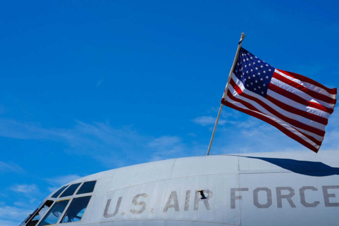 Close-up of a U.S. Air Force aircraft with an American flag waving against a blue sky
