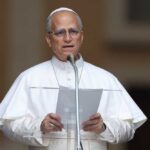 A religious leader speaking at a podium outdoors