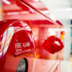Close-up of a red fire alarm with a push button and telephone label
