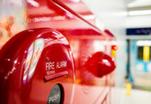Close-up of a red fire alarm with a push button and telephone label
