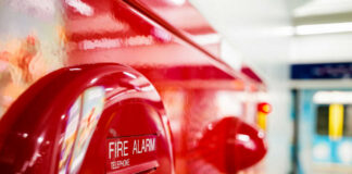 Close-up of a red fire alarm with a push button and telephone label