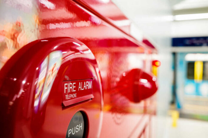 Close-up of a red fire alarm with a push button and telephone label