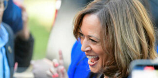 A woman smiling and engaging with a crowd at an outdoor event
