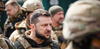 A serious-looking military leader engaged in conversation with soldiers
