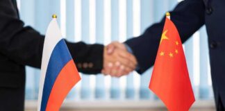 Handshake between two individuals with Russian and Chinese flags in the foreground