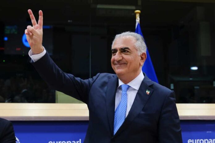 A man in a suit making a peace sign gesture at a podium