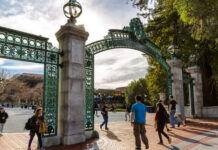 Students walking through a historic university gate on a sunny day