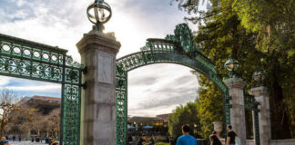 Students walking through a historic university gate on a sunny day