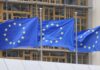 Three European Union flags waving in front of a building