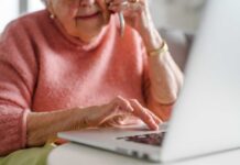 Elderly woman on a phone call while using a laptop