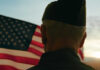 Million Veterans MISS OUT on Huge Tax Break! A veteran in uniform standing in front of an American flag during sunset