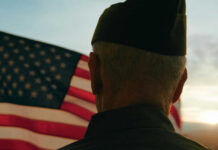 Million Veterans MISS OUT on Huge Tax Break! A veteran in uniform standing in front of an American flag during sunset