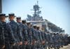 Uniformed naval personnel marching towards a ship