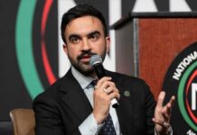 NYC Hiring Rule Sparks Backlash A speaker at a conference holding a microphone and gesturing while speaking