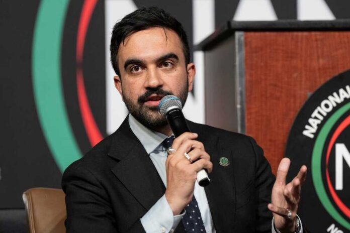 A speaker at a conference holding a microphone and gesturing while speaking