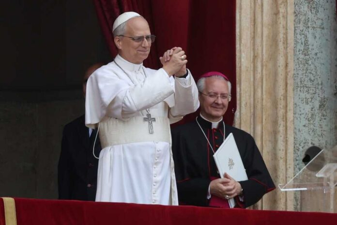 A religious leader in white robes gestures during a public address