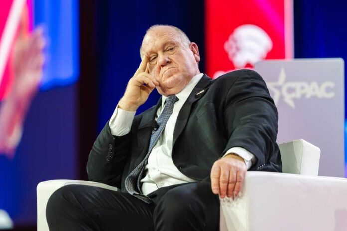 A speaker sitting on a stage with a thoughtful expression at a political conference