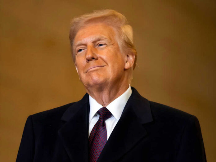 A man in formal attire smiling confidently against a neutral background