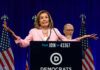 A female politician speaking at a podium with Democratic Party branding