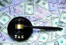 A gavel with the word 'TAX' on it placed on a background of US dollar bills