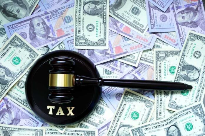 A gavel with the word 'TAX' on it placed on a background of US dollar bills