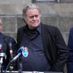 Three men at a press conference with microphones in front of them