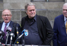 Three men at a press conference with microphones in front of them