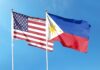 Flags of the United States and the Philippines waving against a blue sky