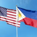Flags of the United States and the Philippines waving against a blue sky