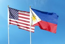 Flags of the United States and the Philippines waving against a blue sky