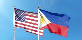 Flags of the United States and the Philippines waving against a blue sky