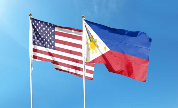 Flags of the United States and the Philippines waving against a blue sky