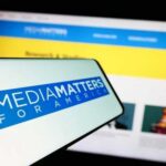 Smartphone displaying Media Matters for America logo in front of a website