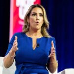 A woman in a blue dress speaking passionately at a conference