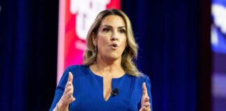 A woman in a blue dress speaking passionately at a conference