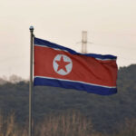 North Korean flag waving against a mountainous backdrop