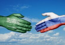 Saudi-Russia Oil Moves: Risky Game in Hormuz! A green hand representing Saudi Arabia and a white hand representing Russia reaching out for a handshake against a blue sky