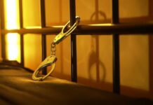 Navy Fugitive Nabbed: Chilling Truth Unfolds Close-up of handcuffs attached to a bed frame