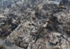 Aerial view of a neighborhood devastated by wildfire, showing burned structures and debris