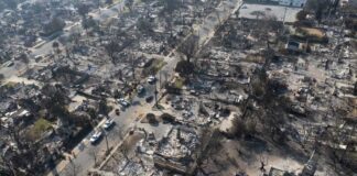 Aerial view of a neighborhood devastated by wildfire, showing burned structures and debris