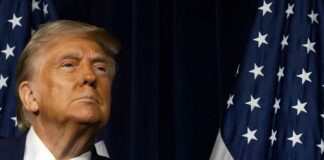 A political figure looking upward beside an American flag