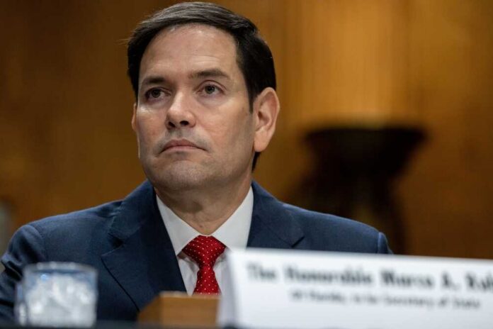 A government official sitting at a hearing with a serious expression
