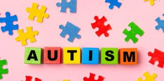 Colorful blocks spelling 'AUTISM' surrounded by puzzle pieces on a pink background