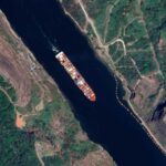 Aerial view of a cargo ship navigating a river surrounded by greenery